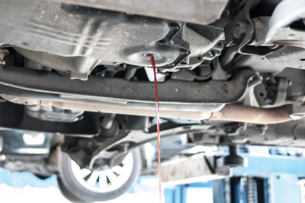 find out what type of auto fluid leak is on the ground on light red fluid leaking from car